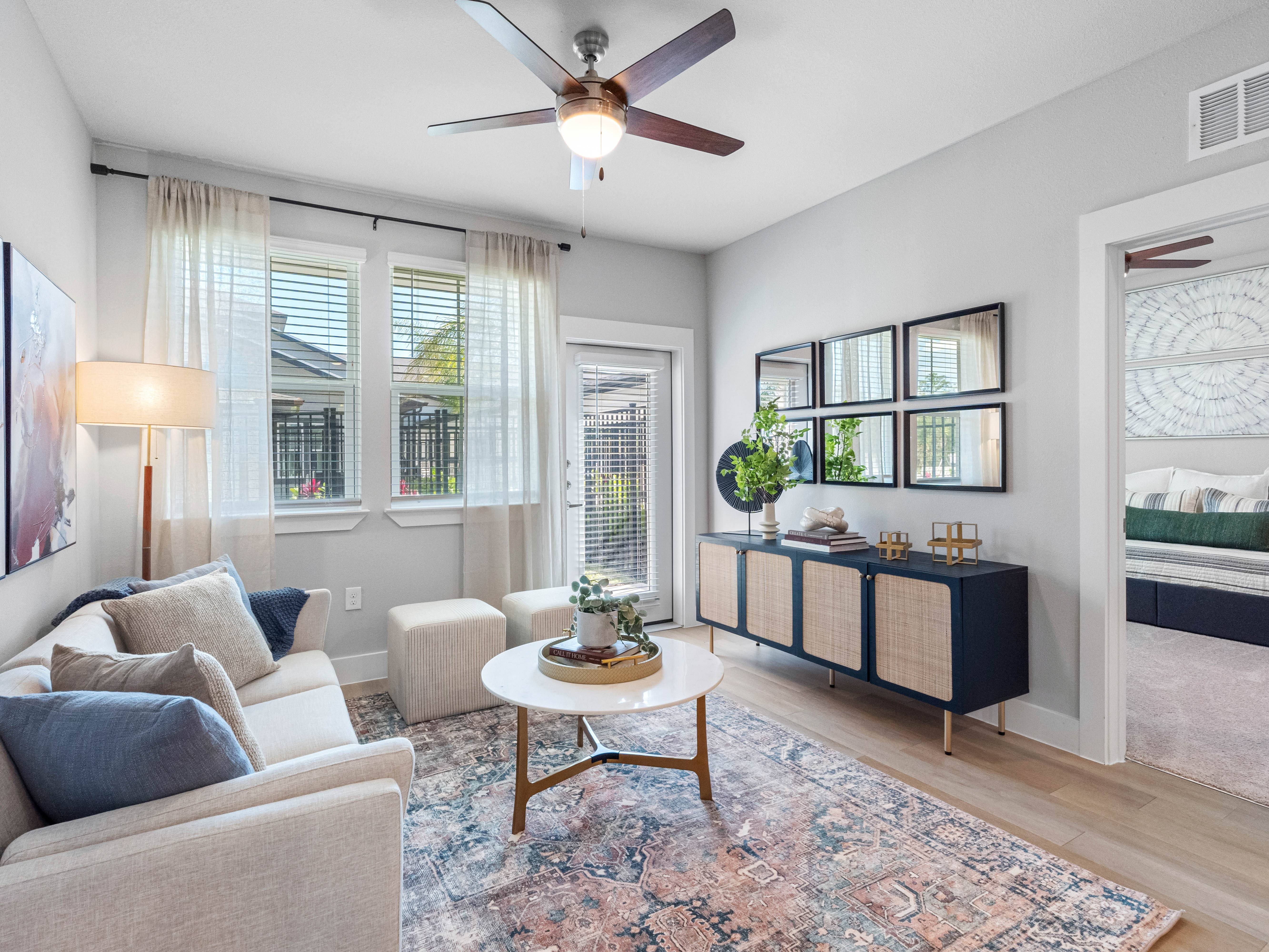 A living room with a beige couch, a white coffee table, and a ceiling fan.